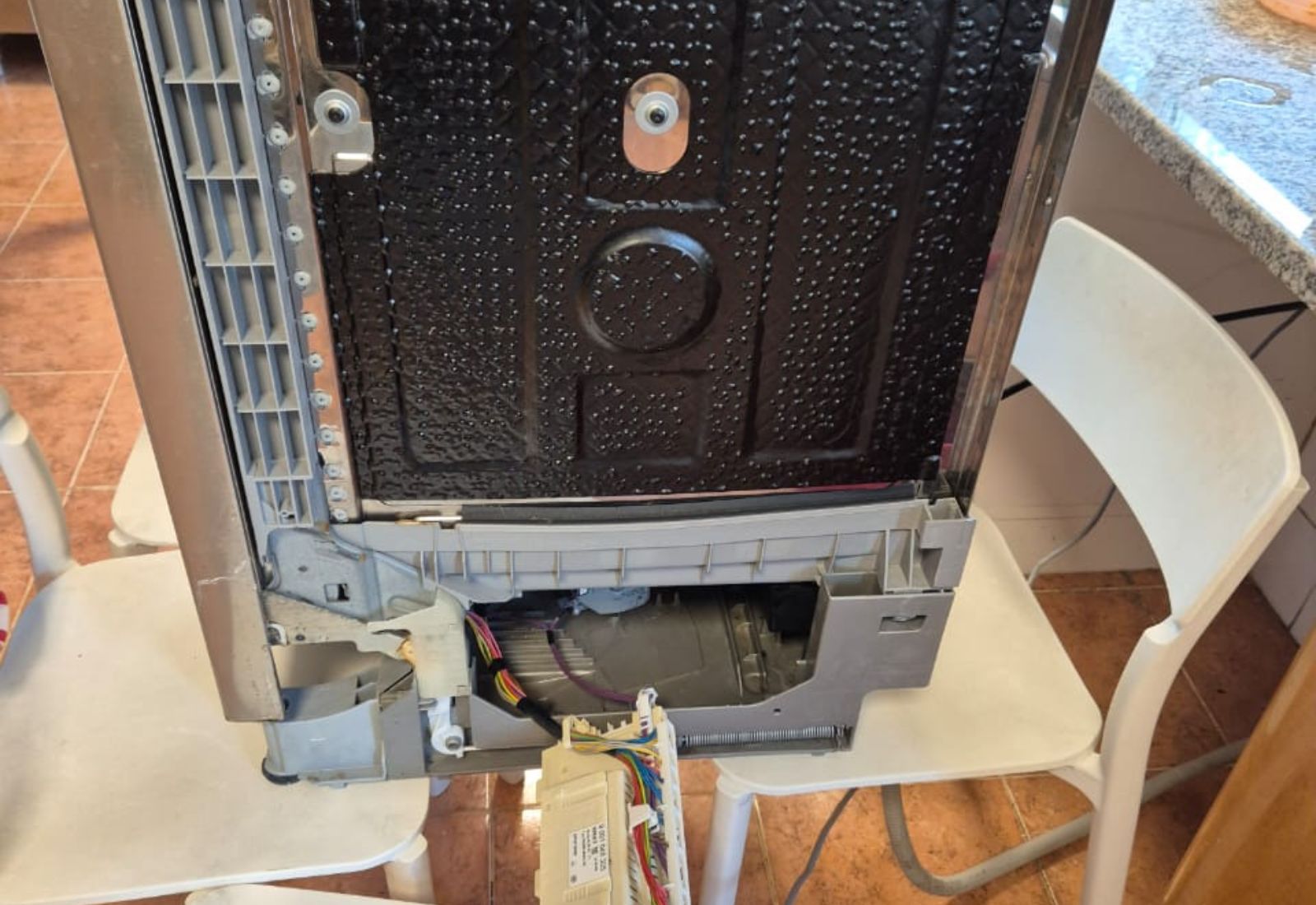 Open dishwasher panel showing wiring and control board during professional dishwasher repair service in Dubai home kitchen.